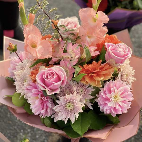Pink and orange mixed bouquet with roses and daisies wrapped in pink paper