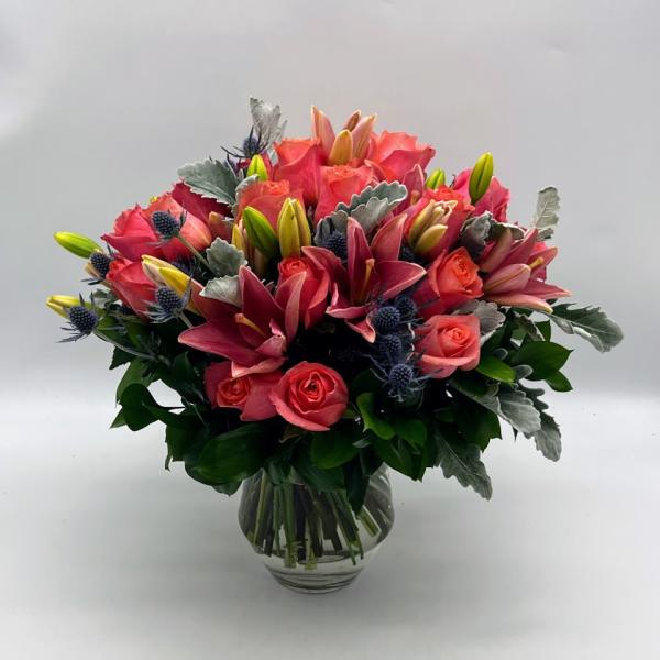 Pink lilies and roses arranged in a clear glass vase