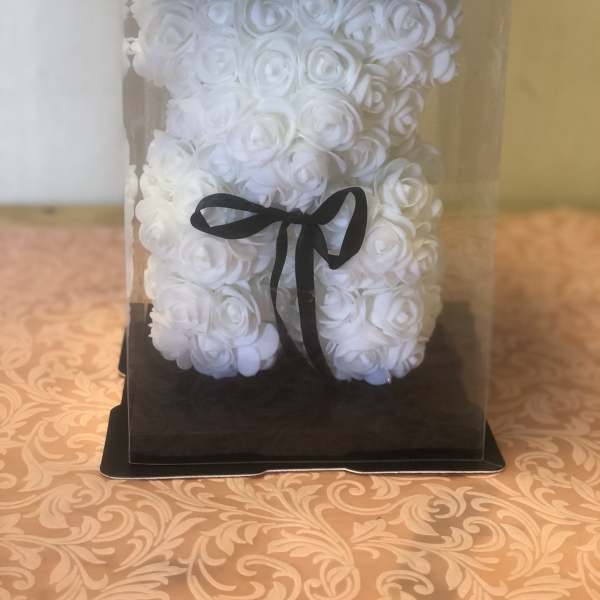 White rose teddy bear in a clear display box with a black ribbon