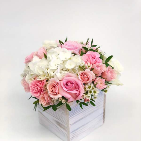 Pink and white roses with hydrangeas in a white wooden box