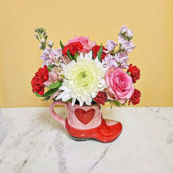Pink and red flower arrangement in a heart-shaped mug and boot container