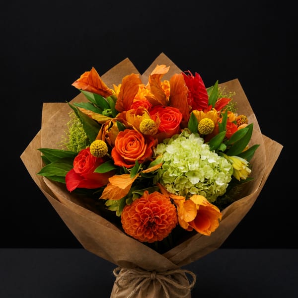 Bouquet of orange and red flowers wrapped in brown paper