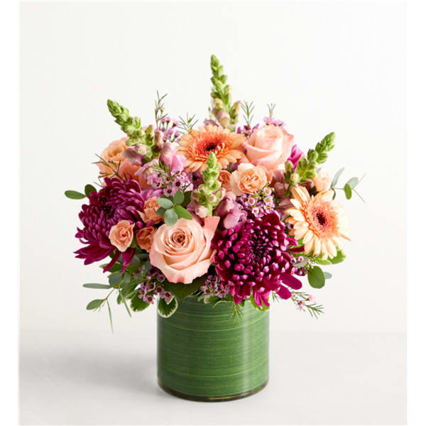 Pink and peach flowers arranged in a green cylindrical vase