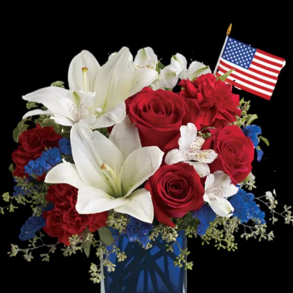 Red roses and white lilies in a blue vase with a small American flag