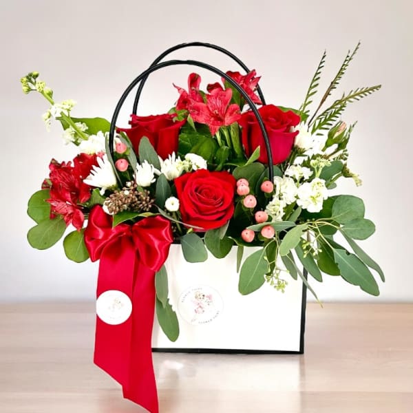Red roses and white flowers in a white gift box with a red ribbon