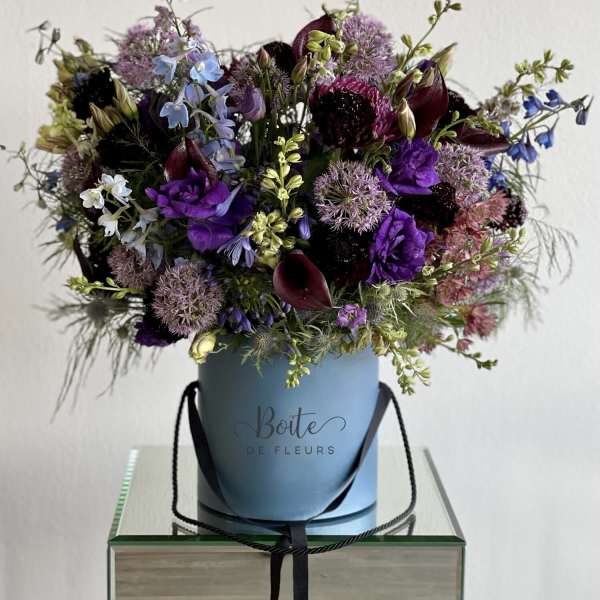 Purple and blue mixed bouquet in a blue hatbox with black ribbon handles