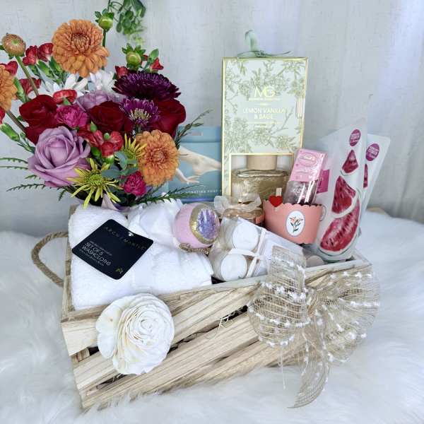 Gift basket with mixed flowers, candles, towels, and bath items