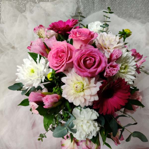 Pink roses and white daisies arranged in a bouquet with tulle wrapping