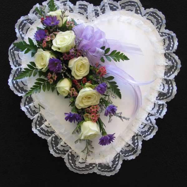 Heart-shaped lace pillow with a floral spray of white roses and purple flowers