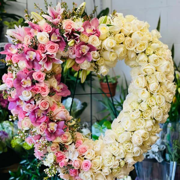 Heart-shaped floral arrangement of pink and cream roses with orchids