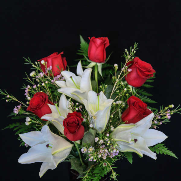 Red roses and white lilies arranged in a dark vase