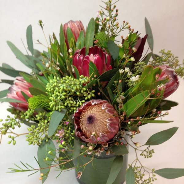 Bouquet of pink protea and greenery in a dark vase