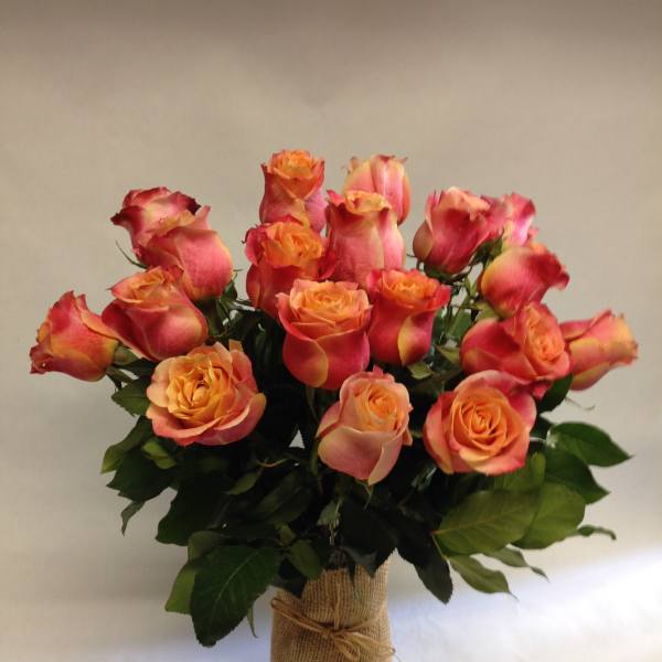 Bouquet of orange-pink roses in a burlap-wrapped vase