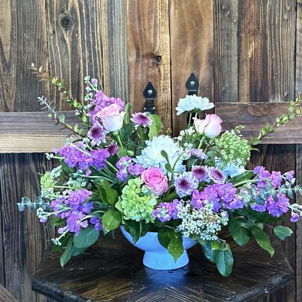 Mixed bouquet of pink, purple, and blue flowers in a blue vase