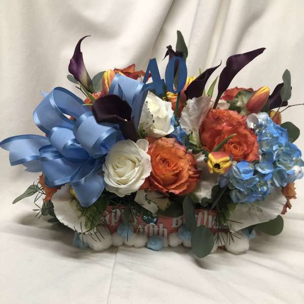 Colorful bouquet with roses, calla lilies, and hydrangeas with a blue ribbon