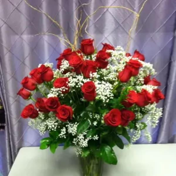 Red roses arranged in a clear glass vase with white filler flowers
