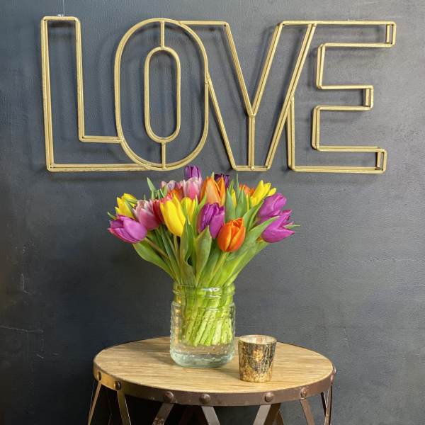Bouquet of multicolored tulips in a glass jar on a table