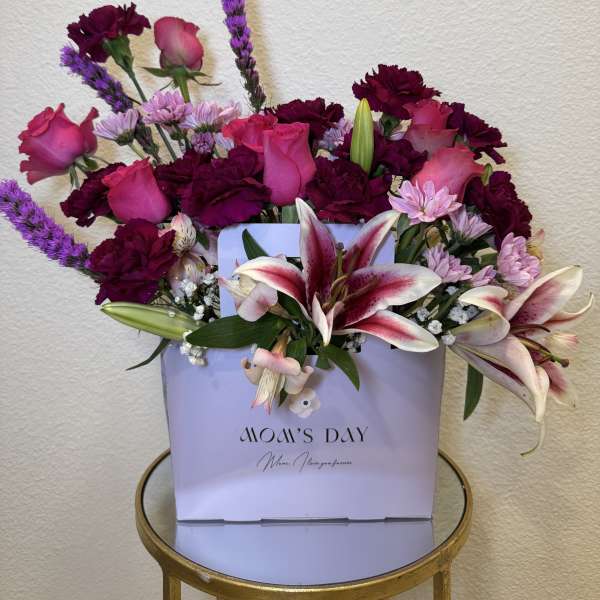 Bouquet of pink roses, lilies, and purple carnations in a gift box