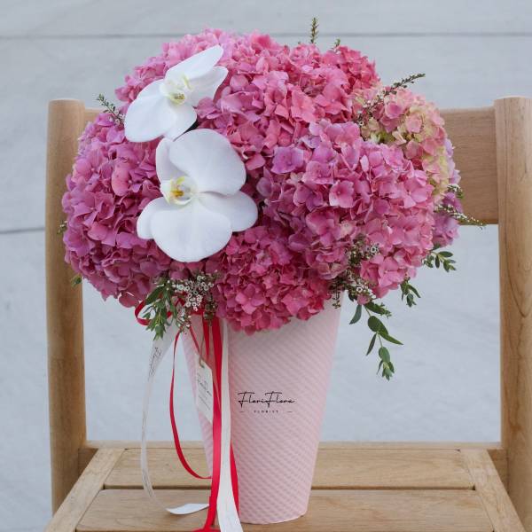 Pink hydrangea arrangement with white orchids in a pink vase