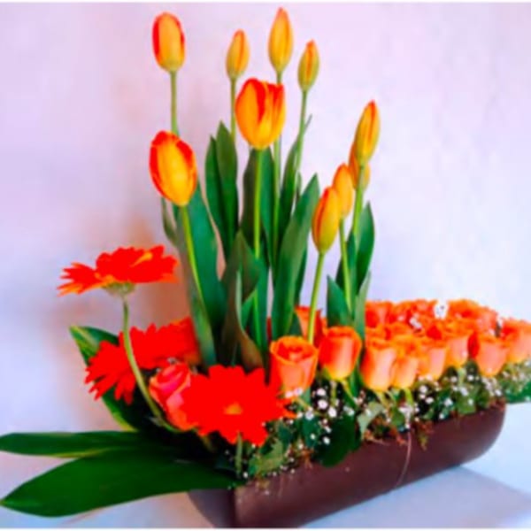 Orange tulips and gerbera daisies arranged in a low brown container