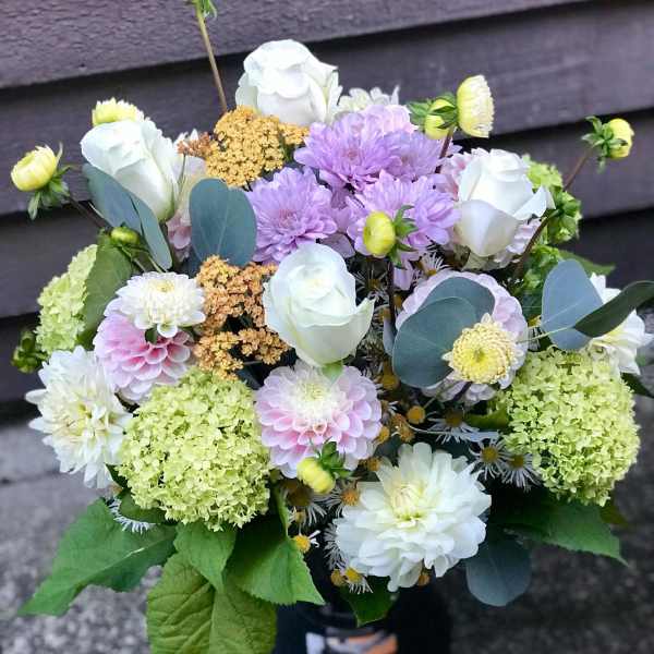 Bouquet of white and lavender flowers with green hydrangeas in a black vase