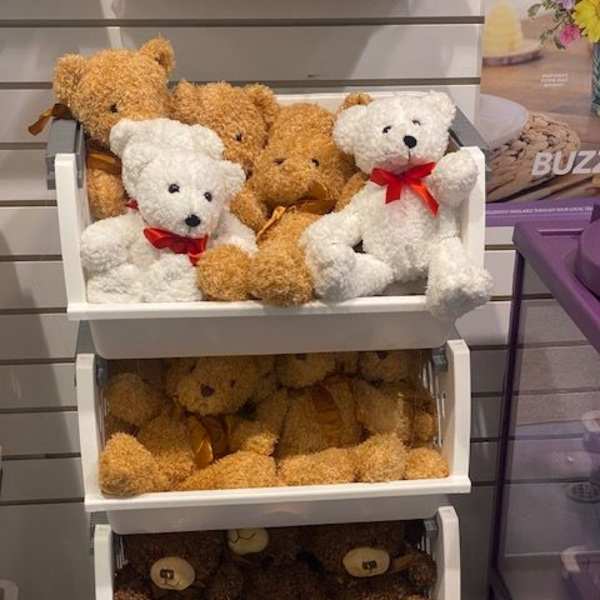 Stacked shelves of teddy bears with red ribbons
