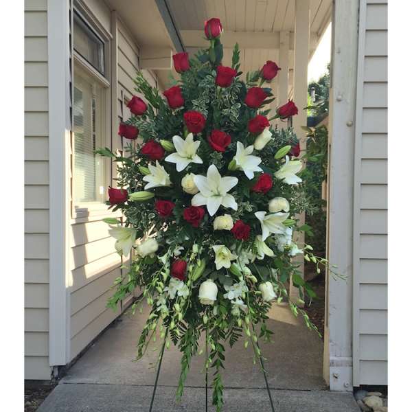 Standing floral spray of red roses and white lilies on an easel