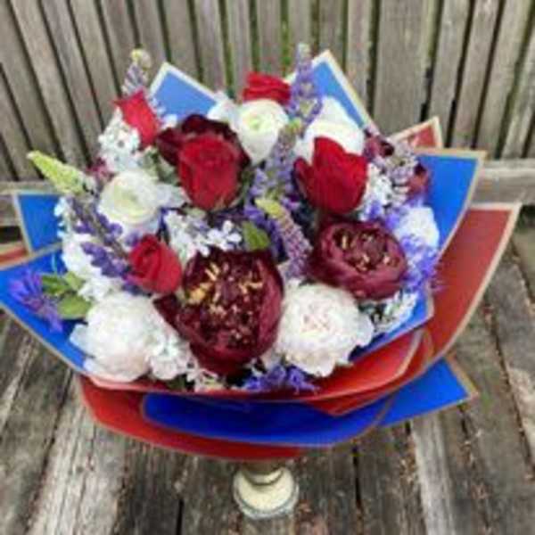 Bouquet of red and white flowers wrapped in red and blue paper