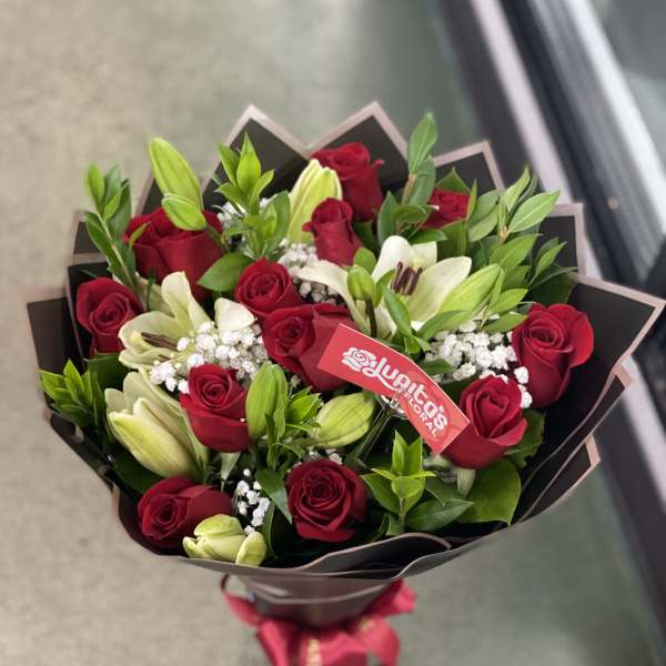 Bouquet of red roses and white lilies wrapped in dark paper