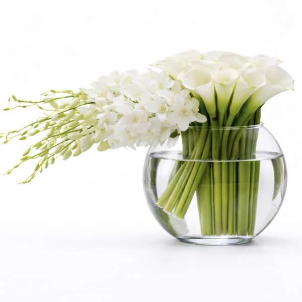 White calla lilies and orchids in a clear glass bowl vase