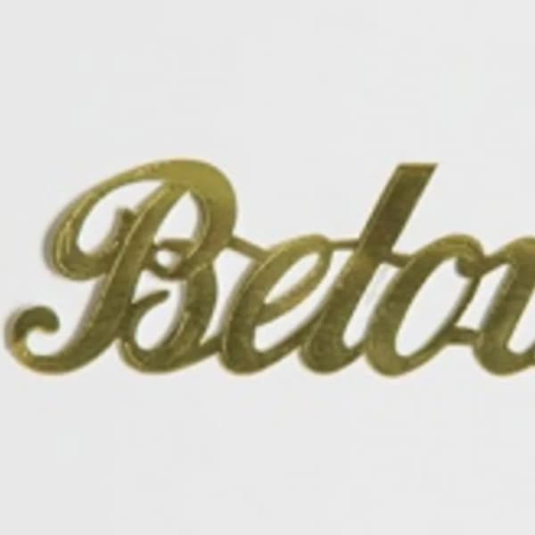 Gold script sign reading "Beloved" on a white background