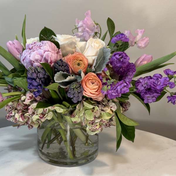 Mixed pink, purple, and white flowers in a clear glass vase