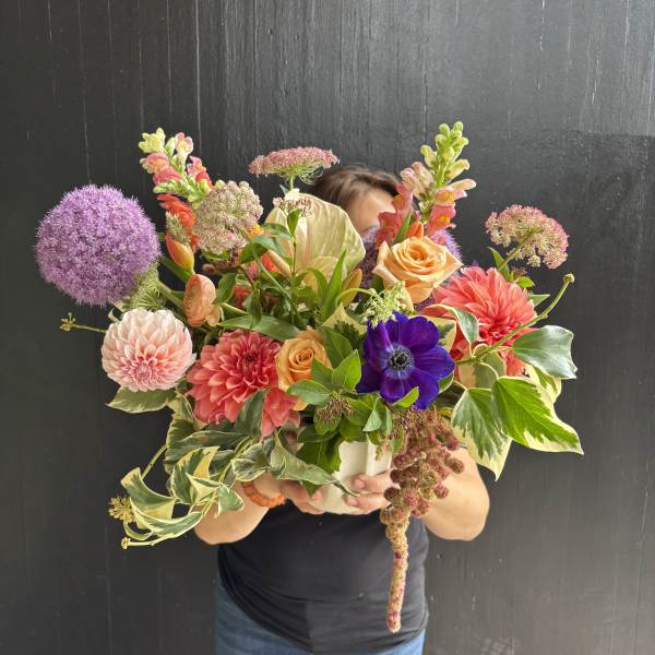 Large mixed bouquet with dahlias, roses, and purple allium in a white vase