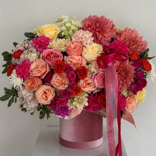 Large pink and peach flower arrangement in a velvet hatbox with ribbon