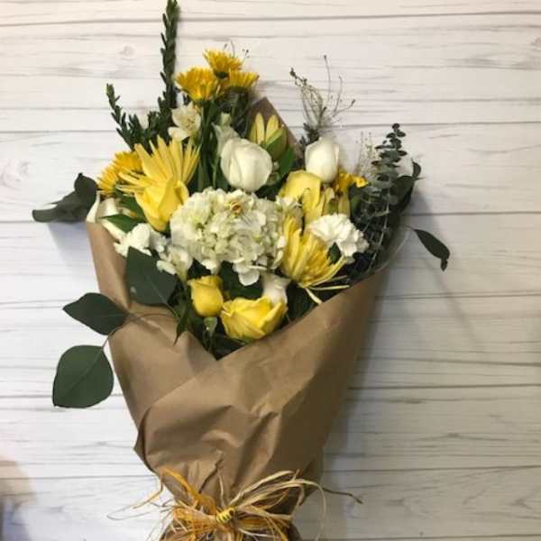 Yellow and white bouquet wrapped in brown paper with a raffia tie