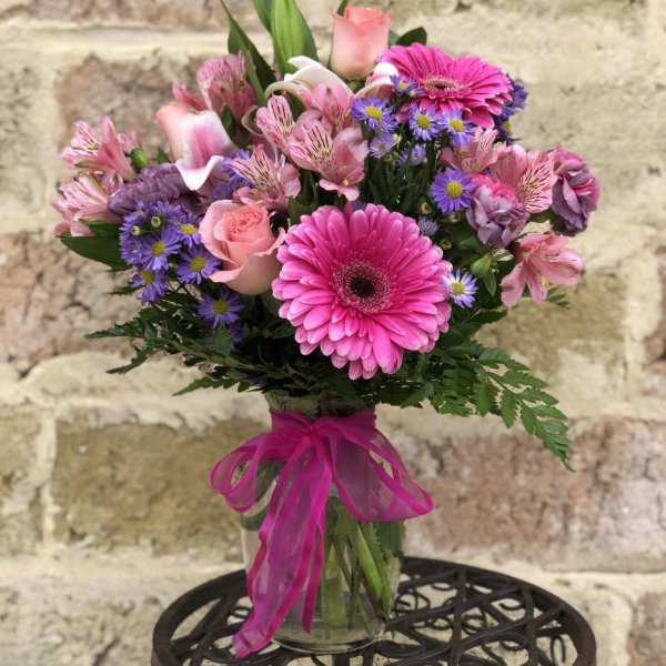 Pink and purple mixed bouquet in a glass vase with a ribbon