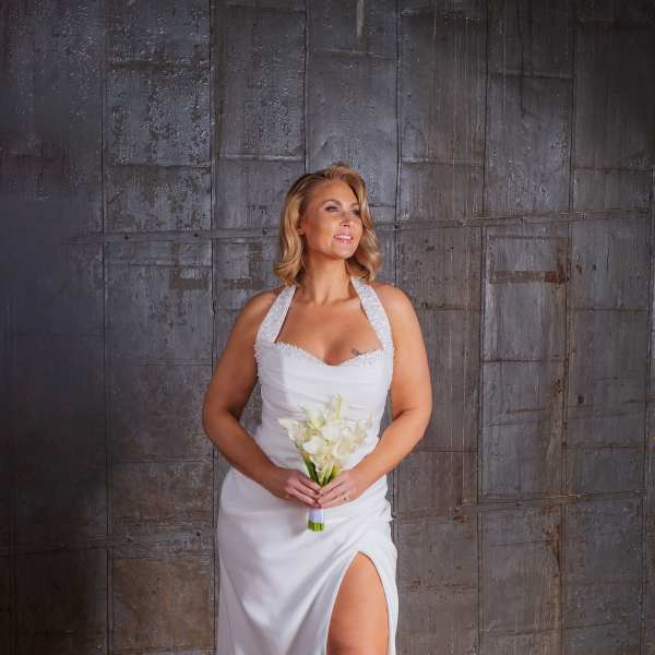 Bride in a white gown holding a small bouquet of white calla lilies