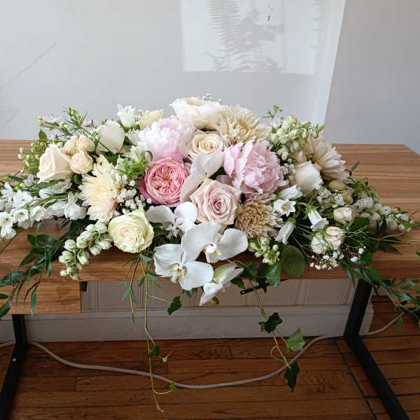 Low pastel floral arrangement with roses, peonies, and orchids on a table