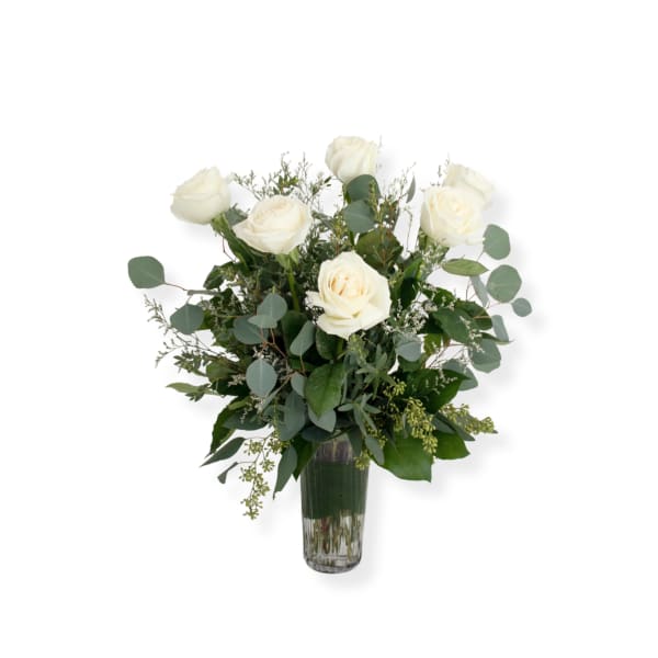 White roses in a clear glass vase with mixed greenery