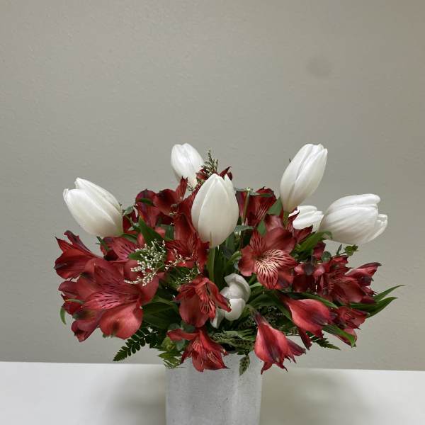 Red alstroemeria and white tulips in a gray vase