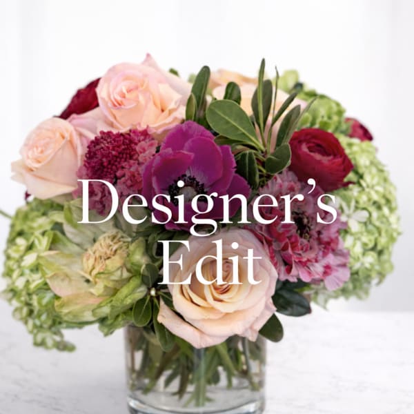 Mixed pink and burgundy flowers arranged in a clear glass vase