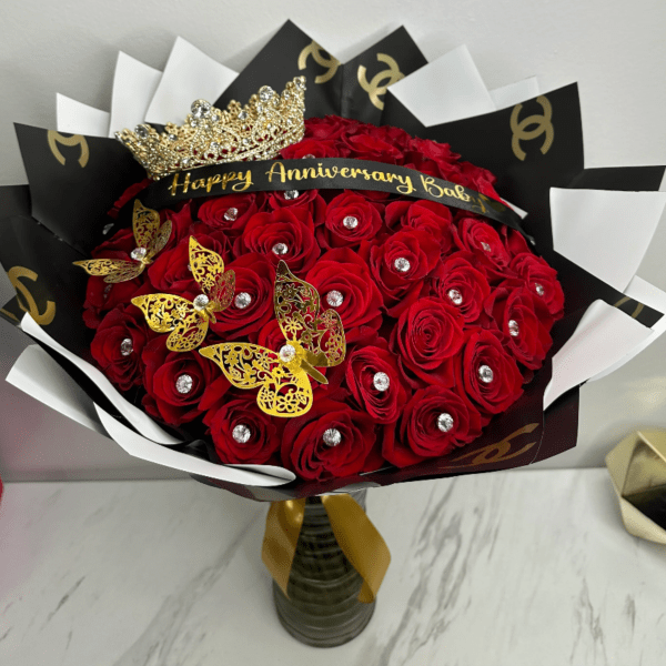 Red rose bouquet with a crown and anniversary ribbon in a vase