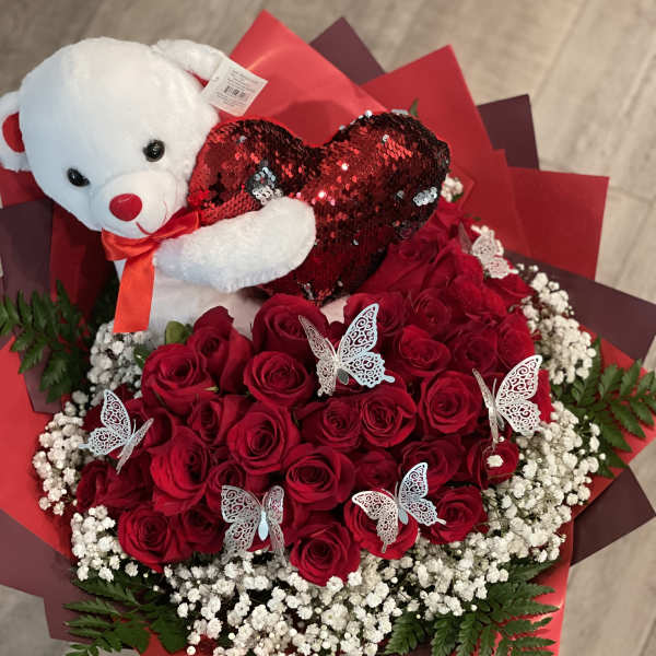 Red rose bouquet with a teddy bear holding a heart and butterfly picks