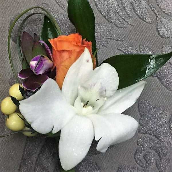 Boutonniere with white lily, orange rose, and purple orchid accents