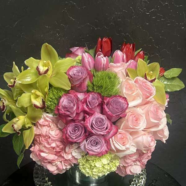 Mixed bouquet of pink roses, hydrangeas, tulips, and green orchids in a vase