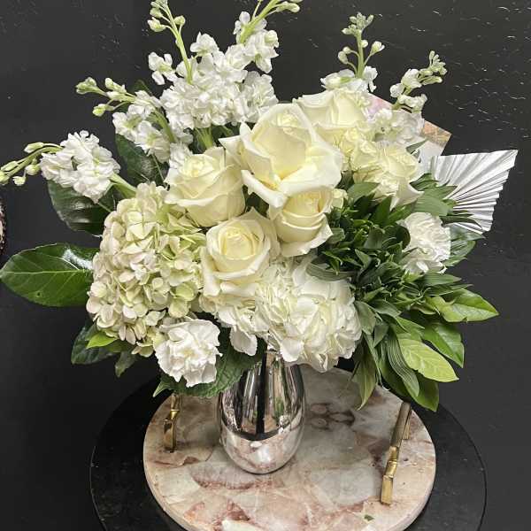 White roses and hydrangeas arranged in a silver vase