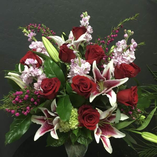 Red roses and pink lilies arranged in a clear vase