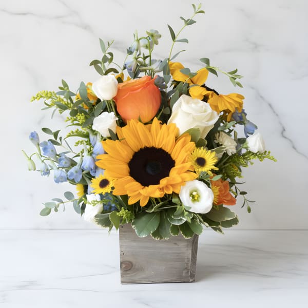 Sunflower bouquet with roses and blue flowers in a wooden box