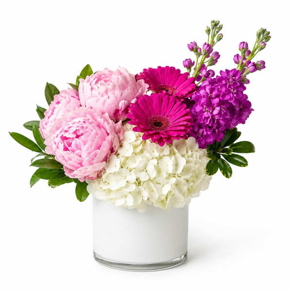 Pink and purple flowers arranged in a white cylindrical vase