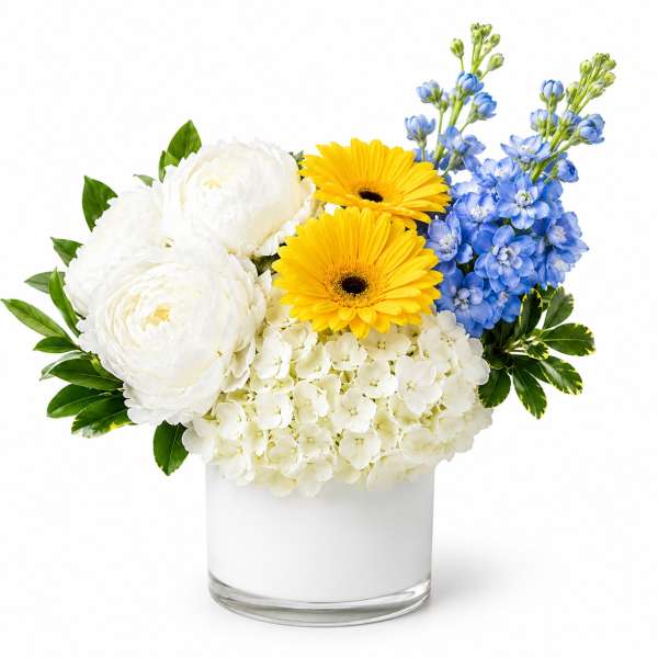 White and yellow flowers with blue blooms in a clear glass vase